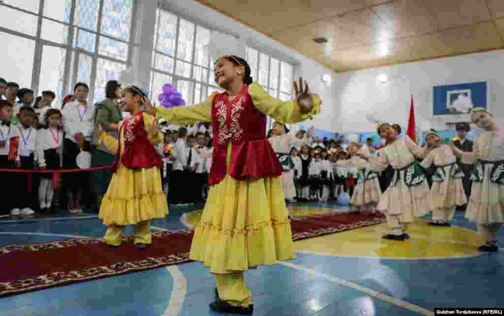 Copiii urmăresc cântece și dansuri tradiționale interpretate de colegi de-ai lor în noul an școlar în Bișkek, Kârgâzstan.