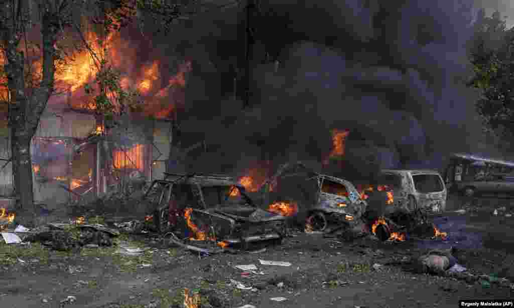 A dead body lies on the ground as cars and a market burn following the missile attack.