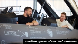 უკრაინის პრეზიდენტი ვოლოდიმირ ზელენსკი და დანიის პრემიერ-მინისტრი მეტე ფრედერიკსენი F-16-ში, დანიის ქალაქ ვოენსის სამხედრო ბაზაზე. 2023 წლის 20 აგვისტო