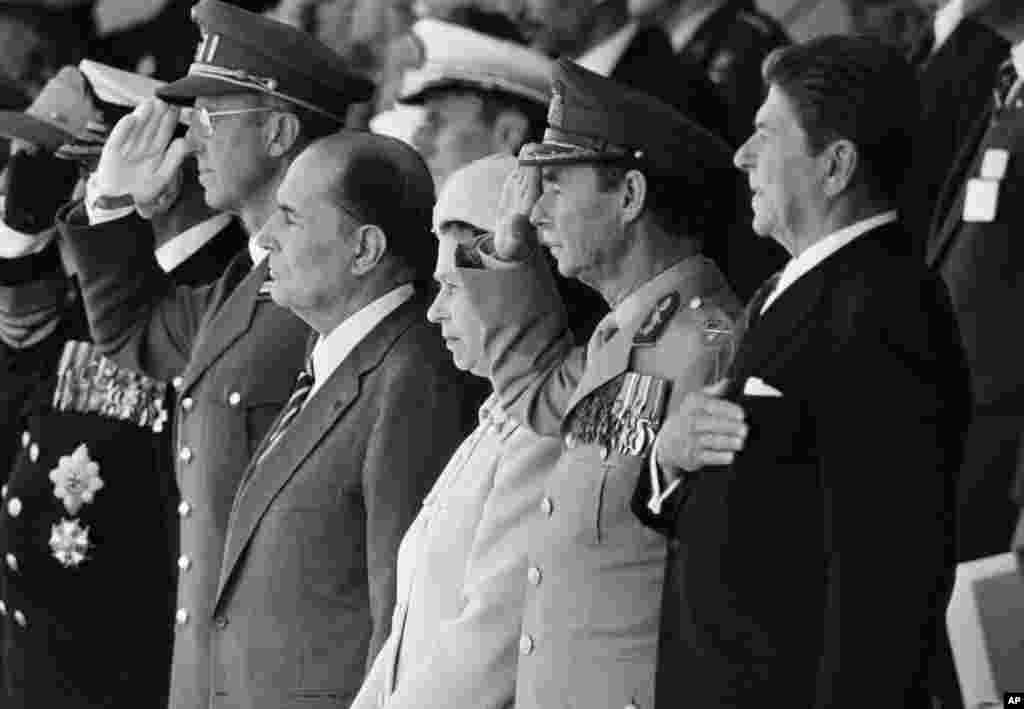 Од лево: кралот Олав од Норвешка (делумно заматен) Кралот Бодуен од Белгија, францускиот претседател Франсоа Митеран, британската кралица Елизабета II, големиот војвода Жан од Луксембург и американскиот претседател Роналд Реган стојат додека се свират химните за време на комеморацијата на 40-годишнината на „Денот Д“, на 6 јуни 1984 година, во Нормандија. Говорот на Реган во Поен ду Хок беше наменет не само како почит на херојството на мажите кои упаднаа на плажите, туку беше и виден како симболична изјава што ја зајакнува посветеноста на САД кон принципите на слобода и демократија во позадината на Студената војна.