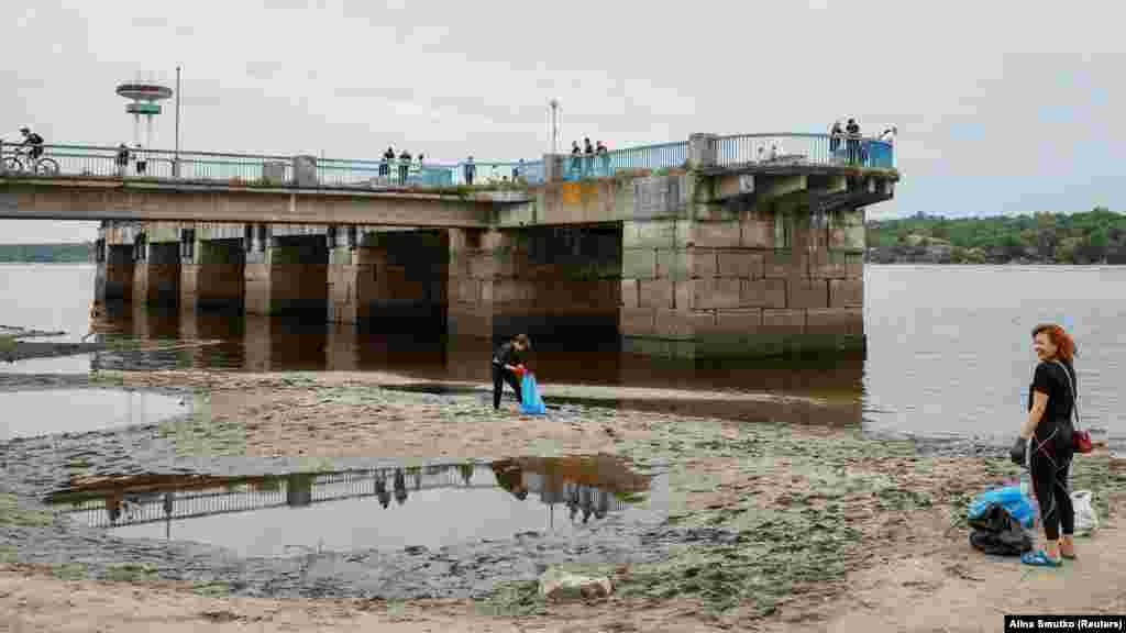 Zaporizzsjaiak a város egyik strandját tisztítják június 10-én, az árvíz visszahúzódása után. Az árvizek lépfenével fertőzöttek is lehetnek
