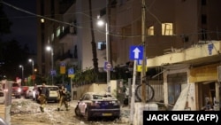Anëtarët e forcave të sigurisë së Izraelit duke ecur nëpër një rrugë plot rrënoja në Tel Aviv, pas një sulmi me raketë nga militantët palestinezë nga Rripi i Gazës, 7 tetor 2023.
