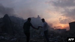 Palestinci traže stvari koje se mogu spasiti ispred ruševina zgrade uništene u izraelskim zračnim napadima u gradu Gazi 8. oktobra 2023.