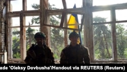 Ukrainian soldiers stand in front of a Ukrainian flag they raised at a location given as the Donetsk village of Blahodatne, which Kyiv claimed to have liberated on June 11. 