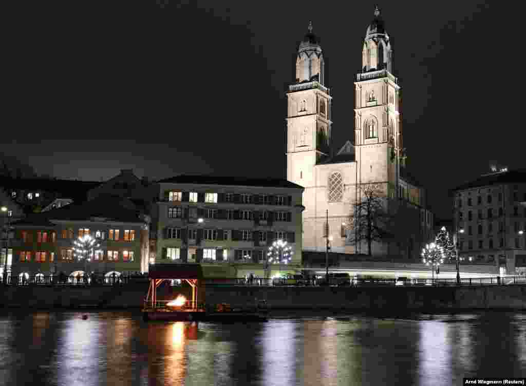 A Grossmünster templom előtt adventi gyertyaként a remény lángja ég a Limmat folyón Zürichben. 