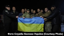 Disa ushtarë të liruar pozojnë për fotografi duke mbajtur flamurin kombëtar të Ukrainës. Fotografi nga arkivi.