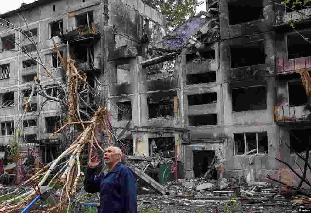 Një banor lokal qëndron pranë ndërtesave të dëmtuara nga sulmet ruse në rajonin ukrainas të Donjeckut.