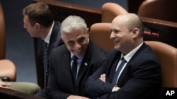 Izrael miniszterelnöke, Naftali Bennett (jobbról) és Jair Lapid külügyminiszter beszélget a parlament feloszlatásáról döntő szavazás előtt Jeruzsálemben 2022. június 30-án