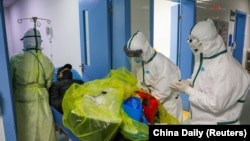Medical workers in protective suits move a virus patient at an isolated hospital ward in Wuhan on February 6.