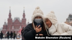 Млад мъж и жена с медицински маски на Червения площад в Москва