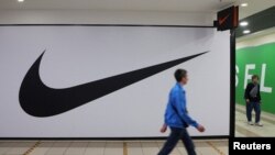 Njerëzit duke kaluar pranë një dyqani të mbyllur të Nike-s në Shën Petersburg, Rusi. 