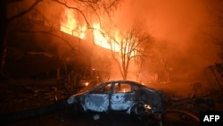 Një veturë e djegur shihet pranë një shtëpie të përfshirë nga zjarri si pasojë e sulmeve ruse me dronë në Harkiv, Ukrainë, 11 qershor.
