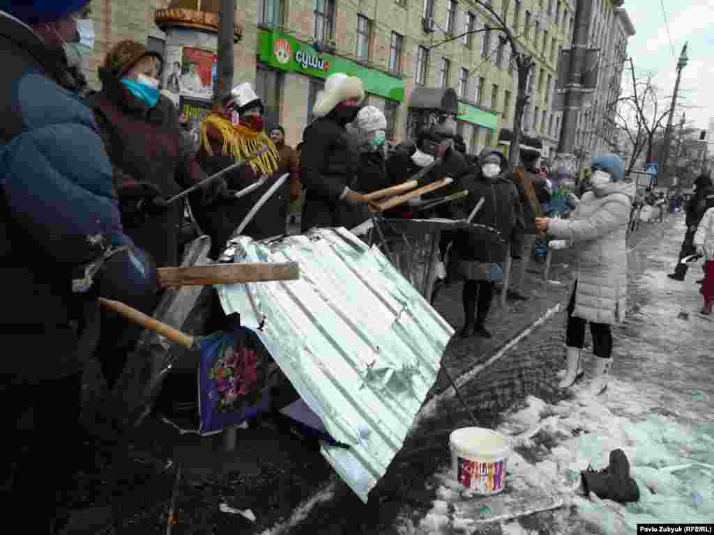 Протестующие бьют палками по железу. 