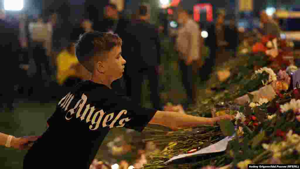 Un băiat a adus flori la memorialul improvizat din Kazan.