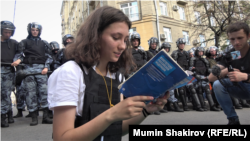 Olga Misik aktivista az orosz alkotmányt olvassa fel a nem engedélyezett ellenzéki tüntetés felszámolására érkező rendőröknek Moszkvában, 2019. július 27-én. 