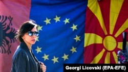 Një grua në Shkup kalon pranë flamujve të Shqipërisë, Bashkimit Evropian dhe Maqedonisë së Veriut. Fotografi ilustruese.