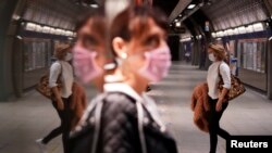 Dy gra mbajnë maska mbrojtëse kundër koronavirusit në një stacion metroje. 