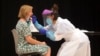 Një punëtore shëndetësore duke testuar një grua për koronavirus.