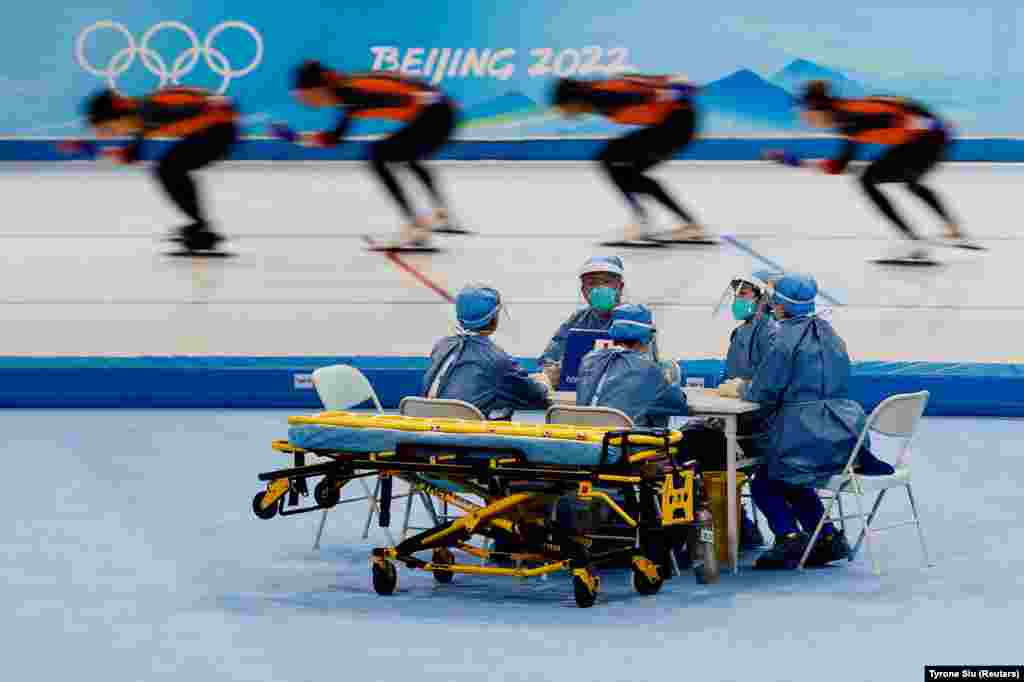Teljes védőfelszerelésben üldögél az egészségügyi személyzet a 2022-es pekingi téli olimpiai játékok gyorskorcsolyaedzésén január 28-án. Az olimpiai játékokat szigorú járványügyi előírások mellett rendezik a kínai fővárosban, a sportolóktól az újságírókig valamennyi résztvevőt teljesen elkülönítik a lakosságtól