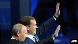 Прем’єр-міністр Росії Володимир Путін і російський президент Дмитро Медведєв (на задньому плані) під час з’їзду партії «Єдина Росія», 24 вересня 2012 року
