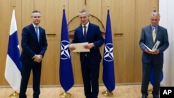 Klaus Korhonen, Finnország NATO-nagykövete (balra), Jens Stoltenberg NATO-főtitkár és Axel Wernhoff, Svédország NATO-nagykövete részt vesz Svédország és Finnország tagfelvételi kérelmének ünnepségén Brüsszelben 2022. május 18-án