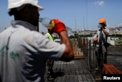 Punëtorët e sektorit të ndërtimzarisë në Kosovë duke pirë ujë teksa punojnë në temperatura të larta. Prishtinë, 19 qershor 2024.