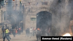 Palestinezët duke ikur pasi policia izraelite hedh gaz lotsjellës dhe granata tymuese në drejtim të tyre. Jerusalem, 10 maj, 2021.
